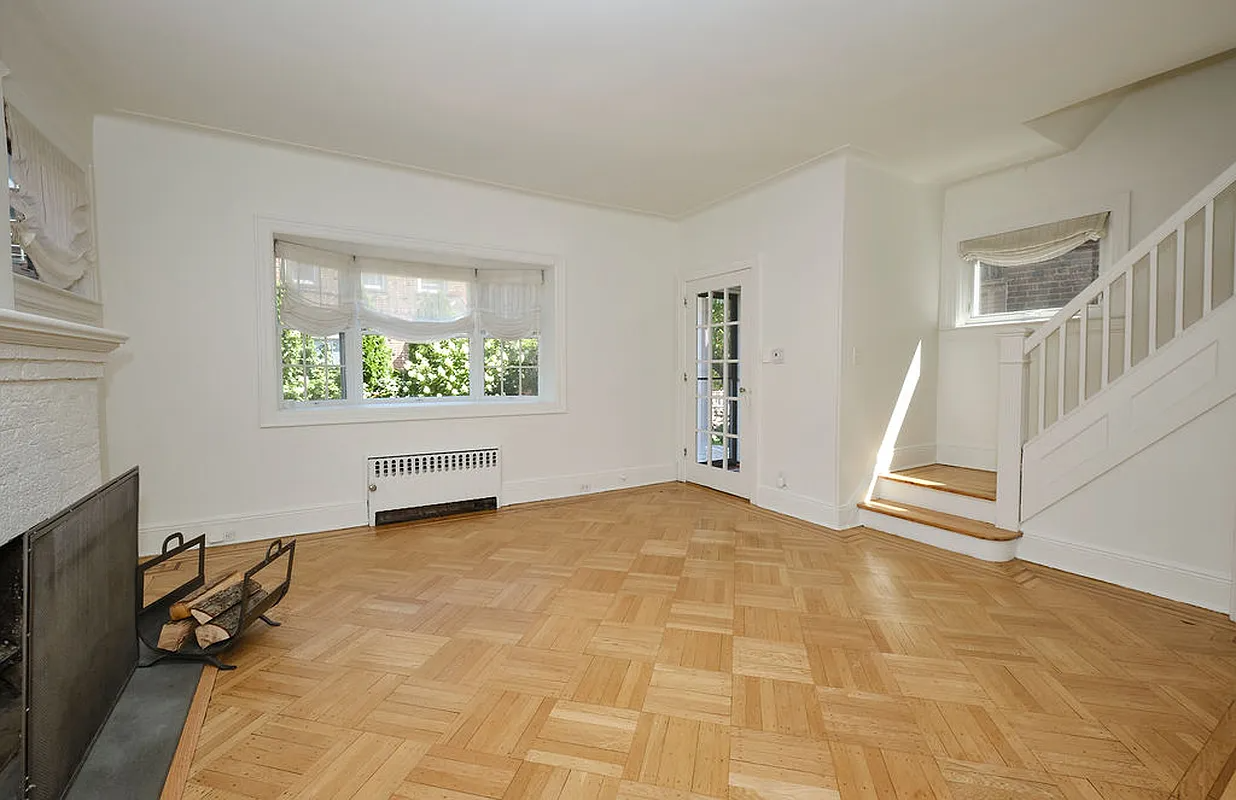 living room with wood floor, brick fireplace, white walls