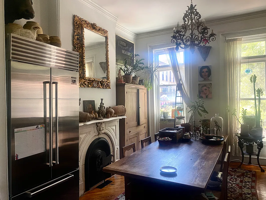 parlor level dining room and kitchen with a large fridge next to the marble mantel