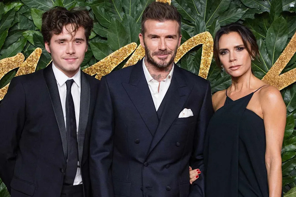 Brooklyn Beckham with his parents, David and Victoria Beckham, at a red carpet event.