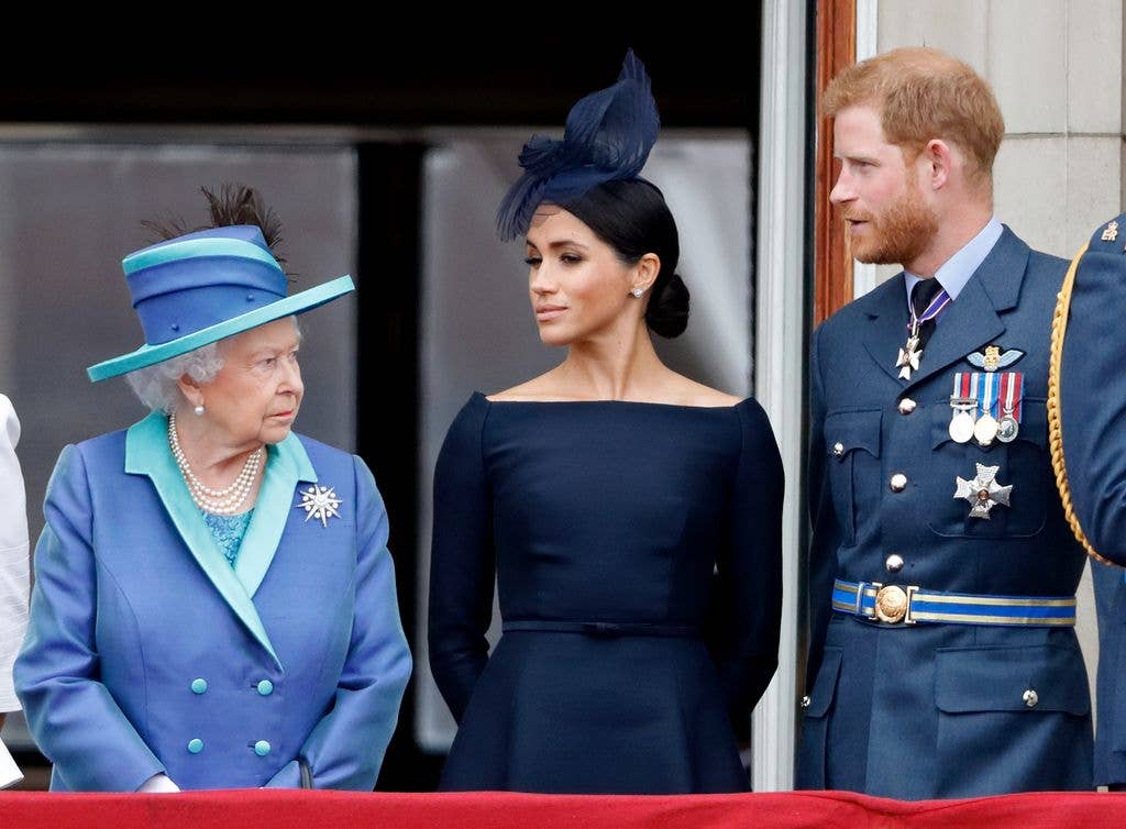 Queen Elizabeth II, Meghan, Duchess of Sussex and Prince Harry, Duke of Sussex watch a flypast to mark the centenary of the Royal Air Force