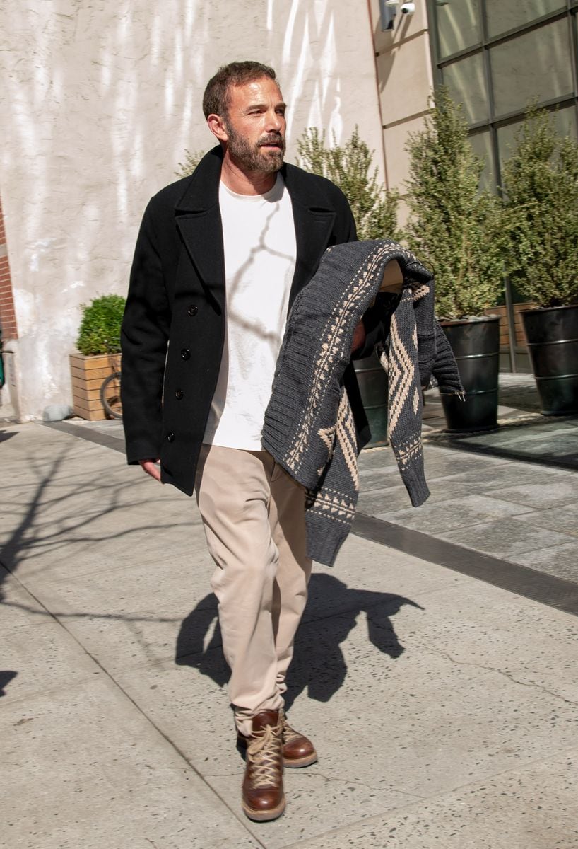 Dressed in his signature polished-casual uniform, Ben kept things classic in a black wool coat layered over a cream knit sweater, paired with beige chinos and sturdy brown lace-up boots. 