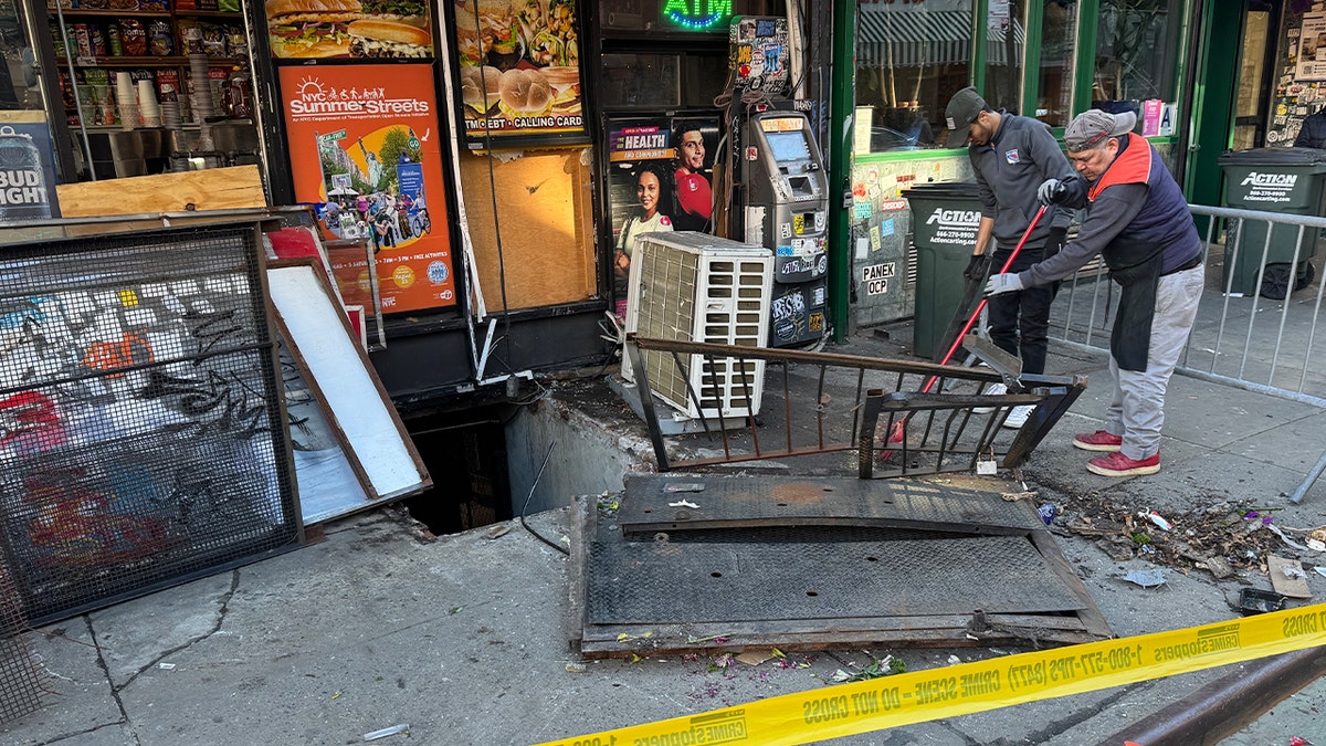 Damaged basement doors outside Manhattan bodega after taxi crash.