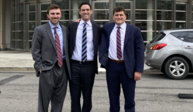 three men in business suits smiling outside courthouse