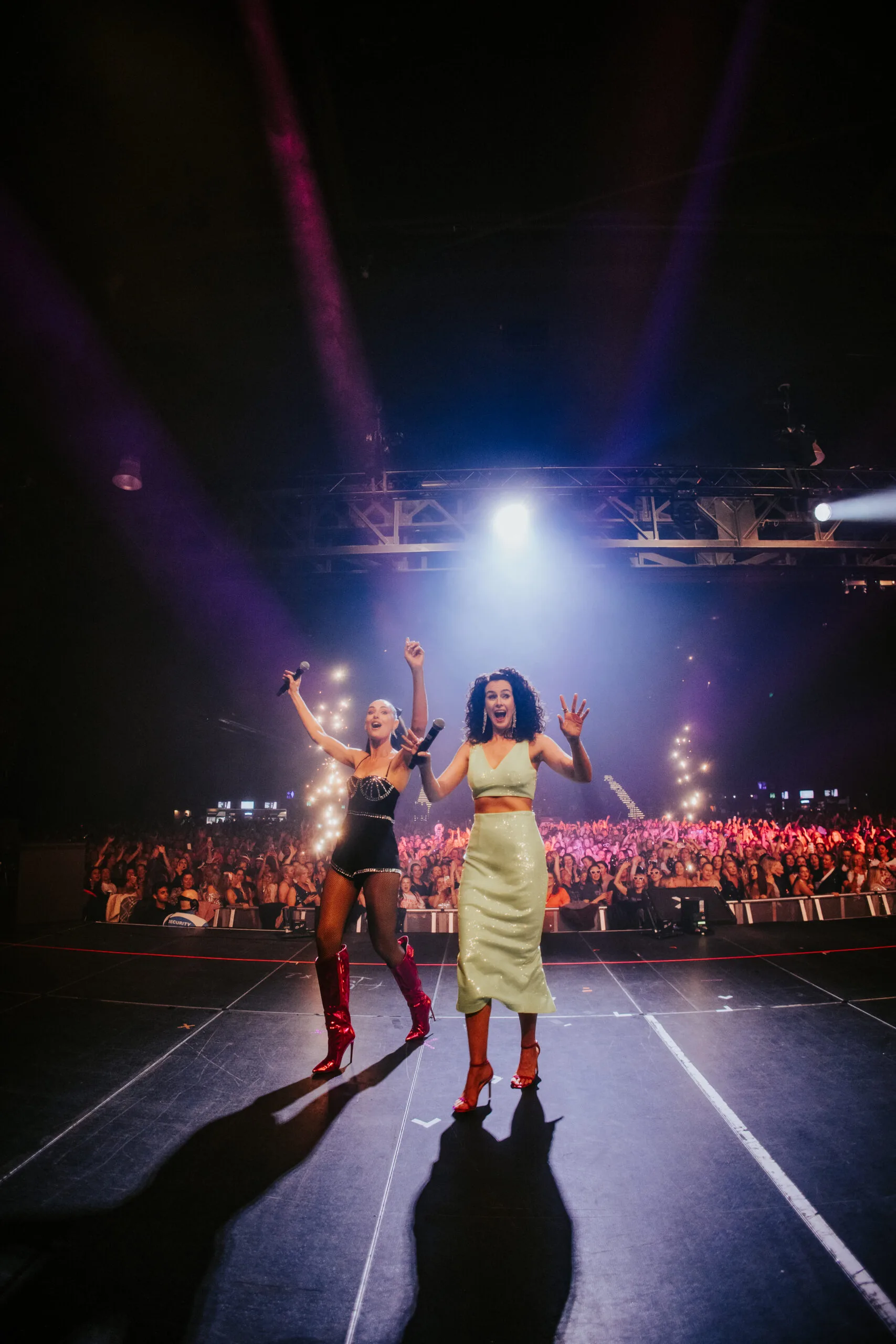 Two women on stage with hundreds of ladies in crowd 
