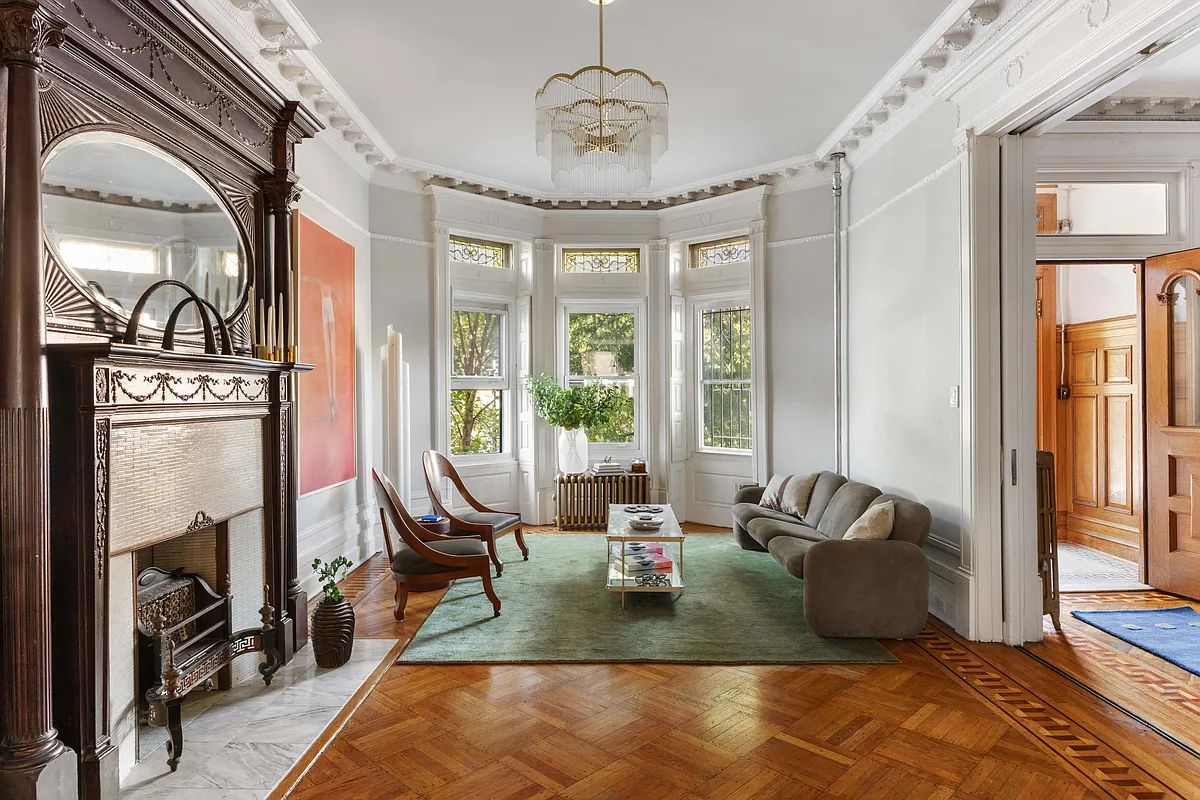parlor with wood floor, stained glass, plasterwork, columned mantel with oval mirror