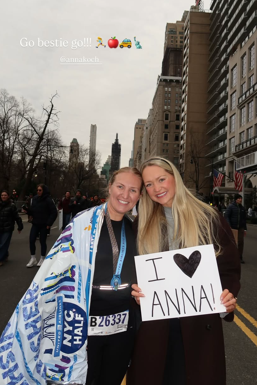 Two women celebrating at a marathon event with a sign.