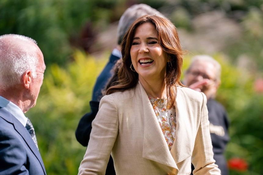 Queen Mary smiles while talking to someone.