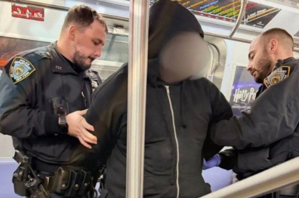 Two police officers arresting a man on a subway.