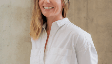 A white woman with shoulder length hair in a white dress shirt smiles