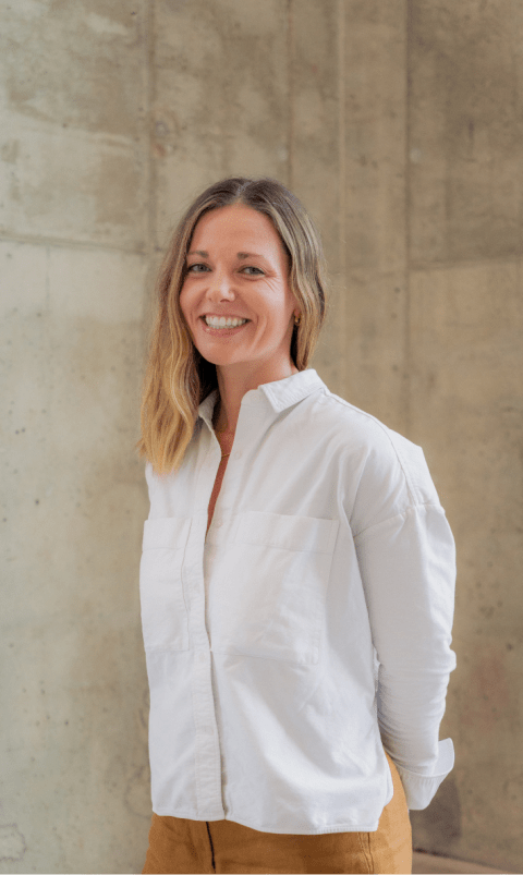 A white woman with shoulder length hair in a white dress shirt smiles