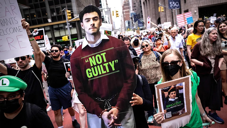 Woman holds a poster of Luigi Mangione during the