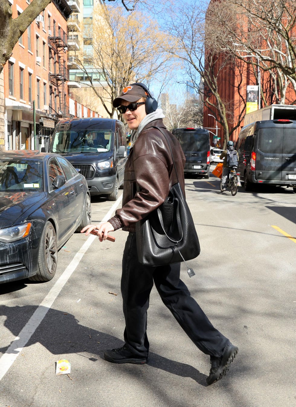 person walking on a city street with vehicles parked alongside