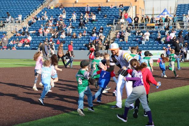 baseball player gives high-fives to kids on field