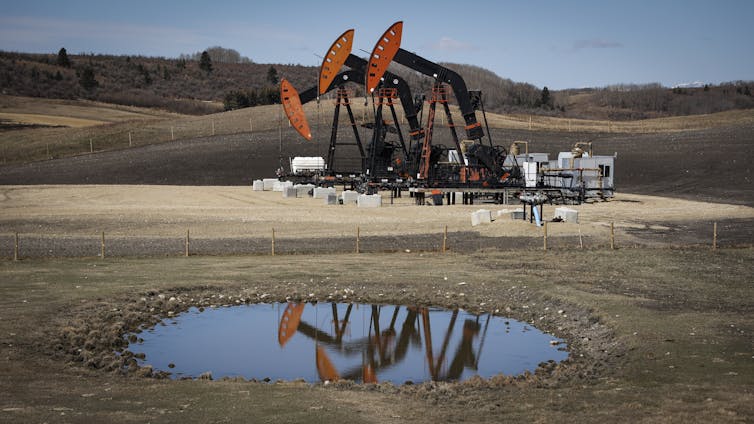 Pumpjacks seen behind a small pond