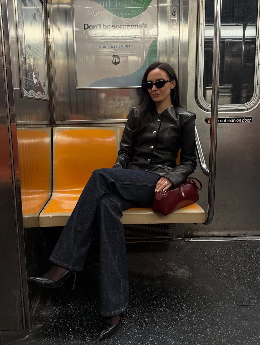 Leather jacket, jeans, heels, red bag and sunglasses on metro.