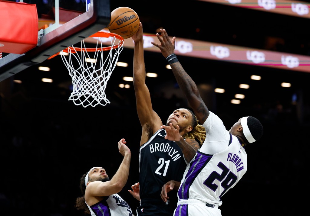 Brooklyn Nets player Noah Clowney (21) shooting over Sacramento Kings players Devin Carter (22) and Daeqwon Plowden (29).