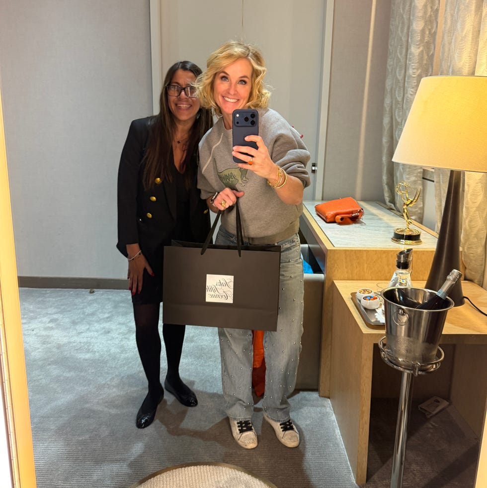 two individuals posing together in a mirror reflection one holding a shopping bag