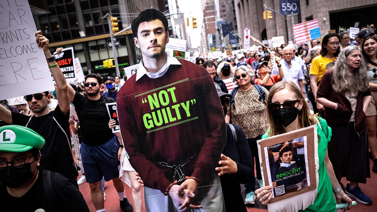 Woman holds a poster of Luigi Mangione during the 