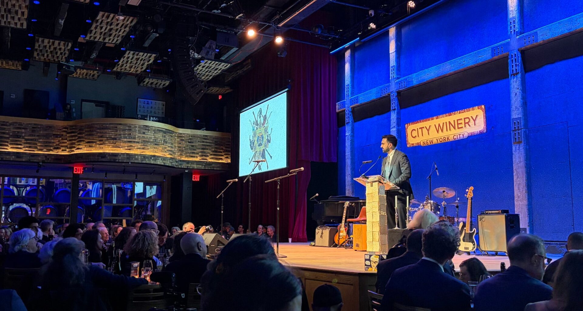 A photo of mamdani speaking on a stage.