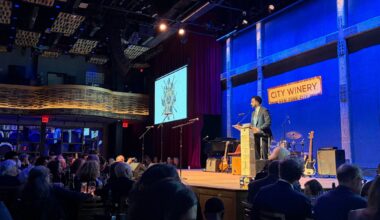 A photo of mamdani speaking on a stage.