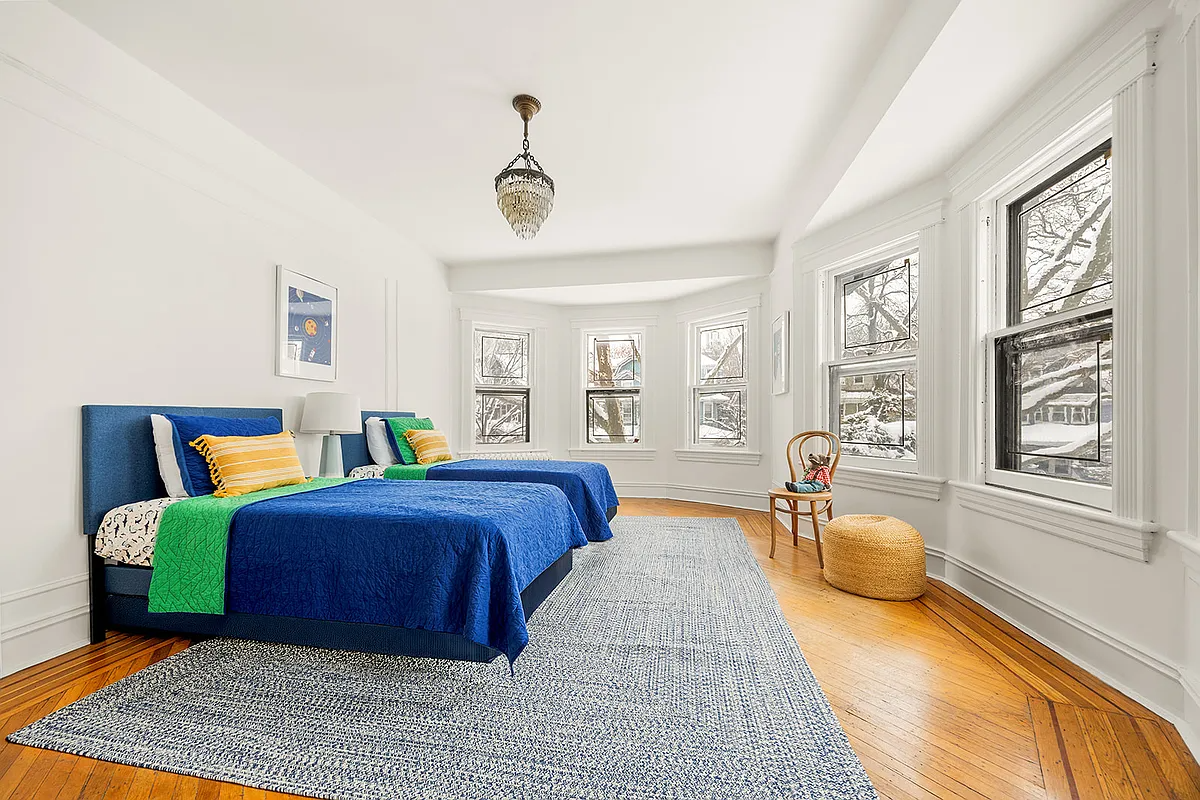 bedroom with wood floor, wall moldings and two exposures
