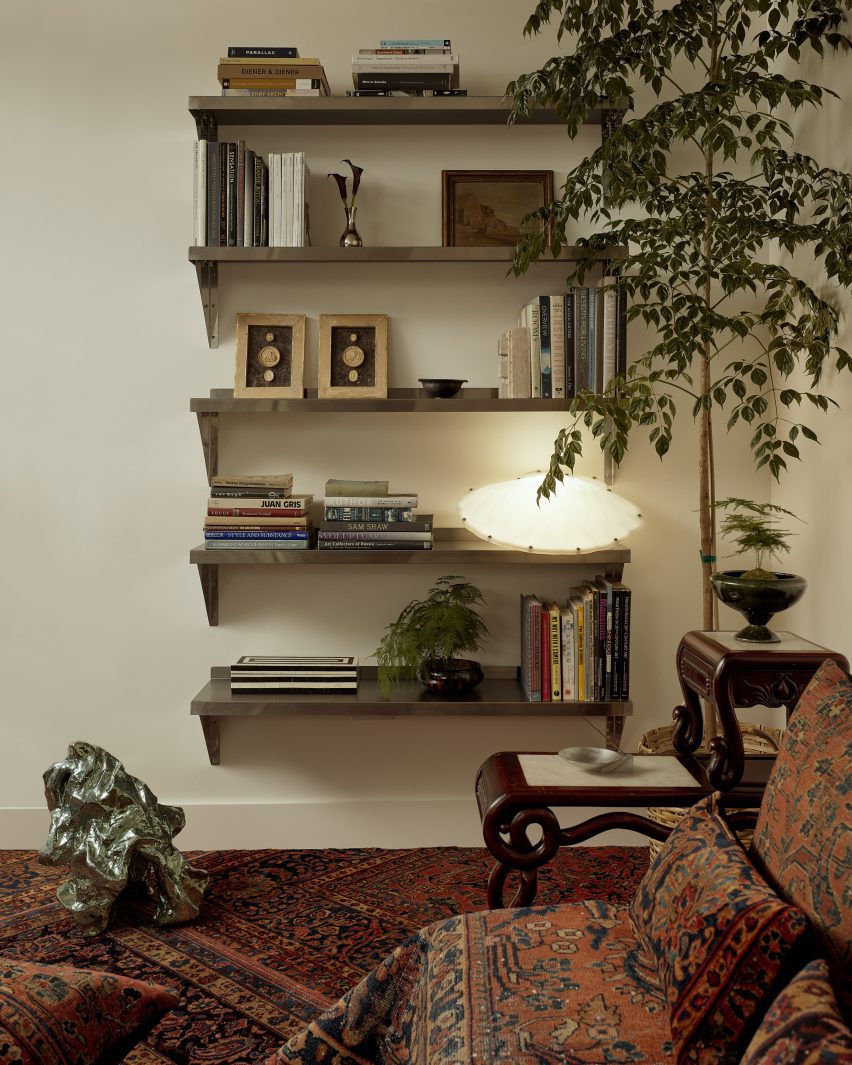 A series of stainless-steel shelves display books and small objects