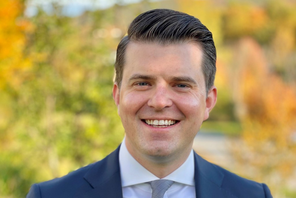 Former Vermont Department of Corrections Commissioner Nicholas Deml smiles in a headshot with fall foliage in the background