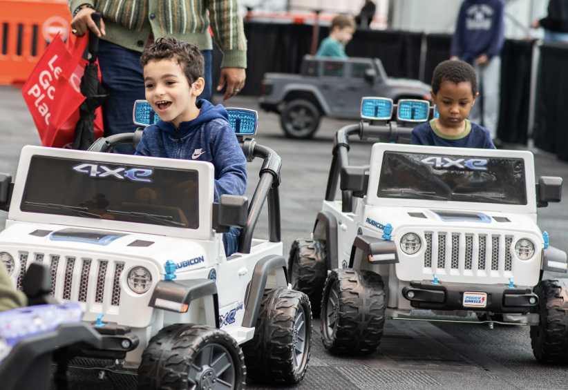 two kids in kid size jeeps driving.