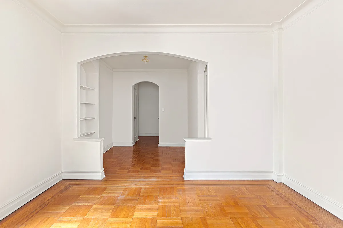 park slope co-op - a half wall with an arched opening separates a living room and a foyer
