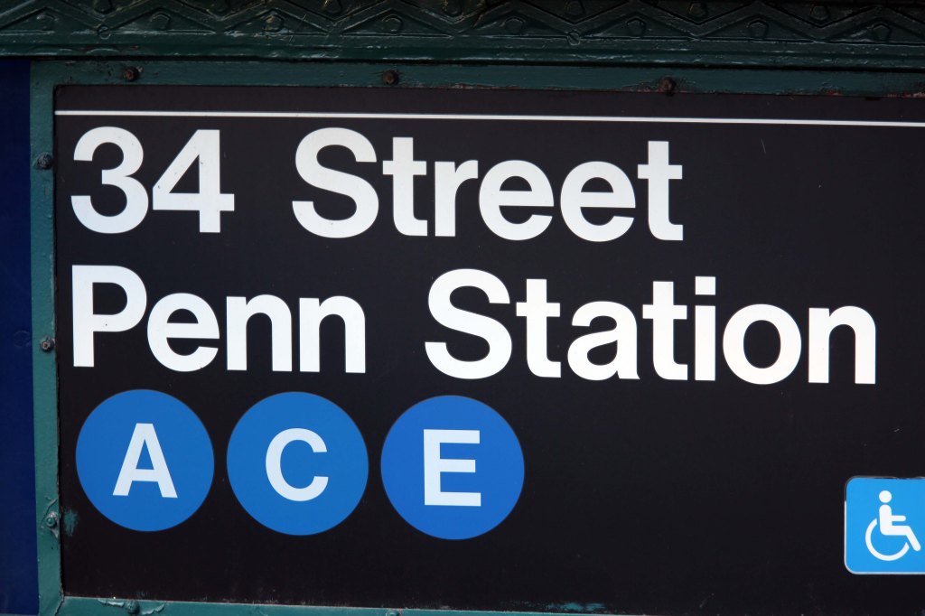 Sign for the 34 Street Penn Station subway stop with blue circles for the A, C, and E lines.