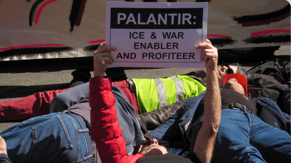 People lie in a city street, some holding up protest signs.