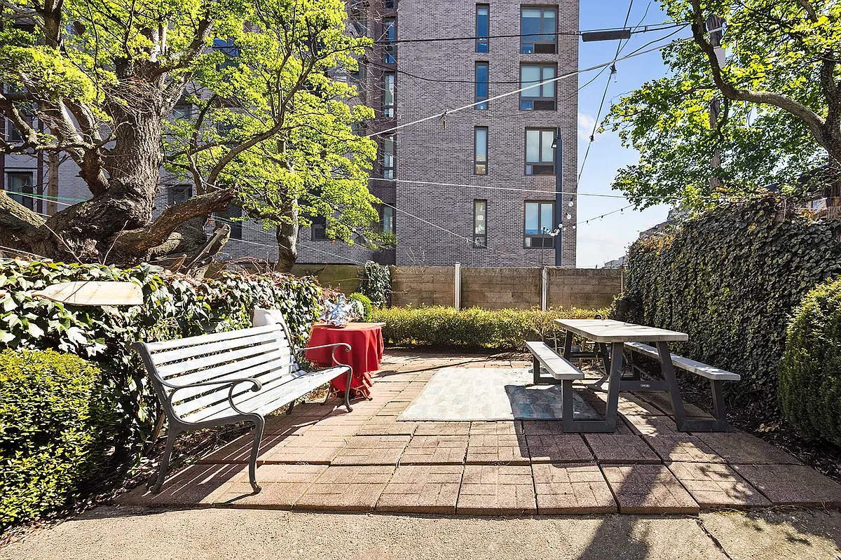 paved rear yard with shrubbery, room for seating
