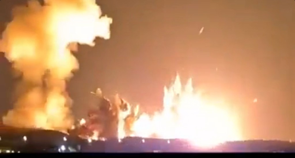 Video still of a large explosion with flames and smoke visible against a dark sky.