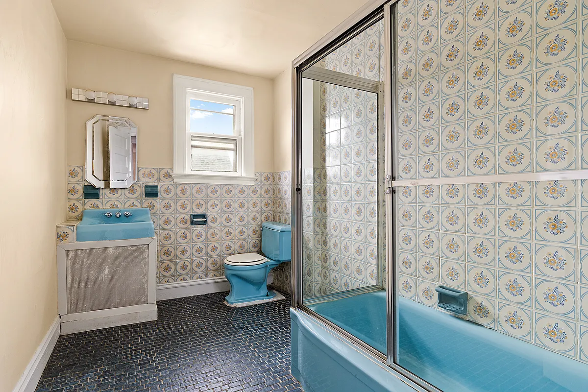 bathroom with vintage blue tub, toilet, sink and floral tile