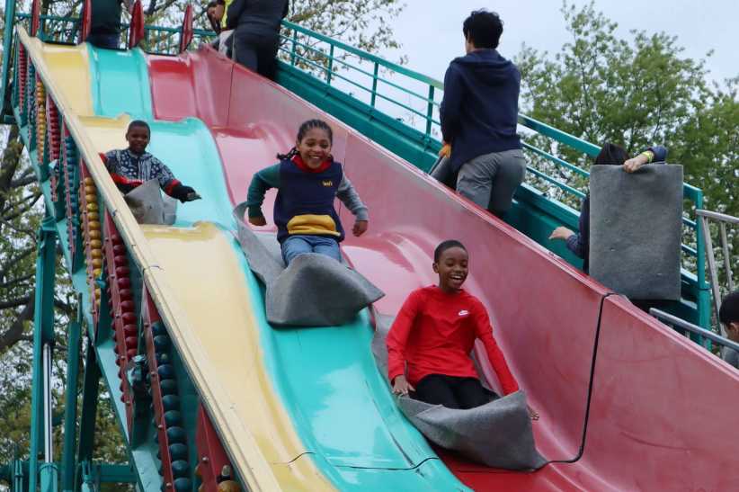 3 children going down a colorful slide. 