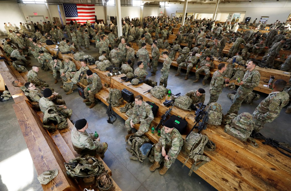U.S. Army paratroopers rest before boarding a transport plane to Europe.