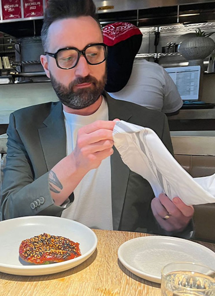 Joshua Fyksen at a Michelin-starred restaurant, holding a napkin with a dish of food on the table.
