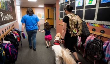 A long-term substitute special education teacher walks with a student as her mother follows with service dog