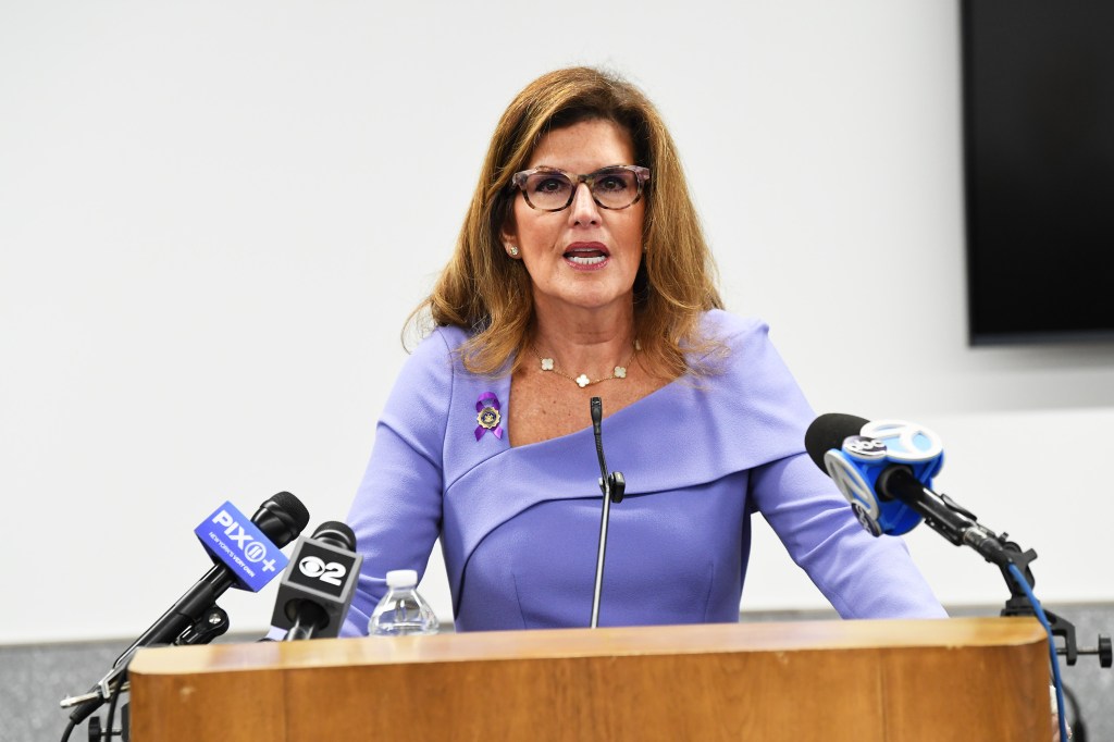 Westchester County DA Susan Cacace speaking at a podium with microphones.