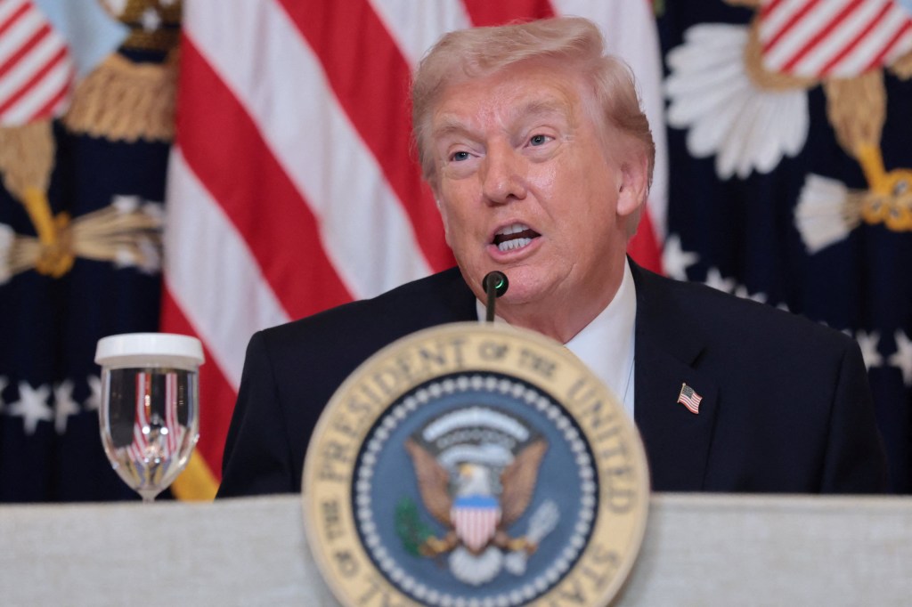 U.S. President Donald Trump speaking at a podium with a microphone and a seal of the President of the United States.