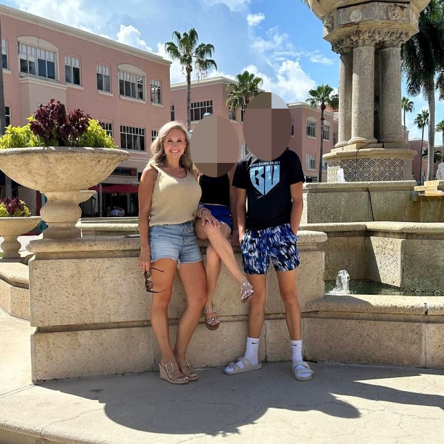 Misty Dawn Clanton Roberts smiling with two people whose faces are blurred.
