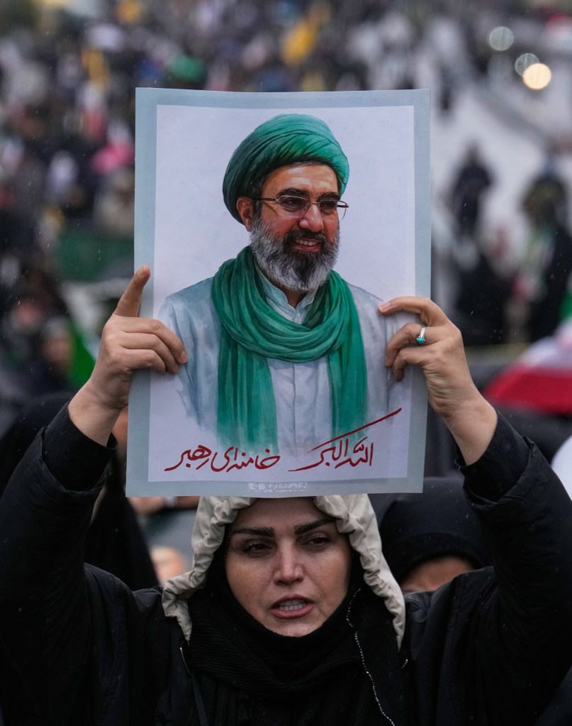A woman holds a poster of Iranian Supreme Leader Ayatollah Mojtaba Khamenei.