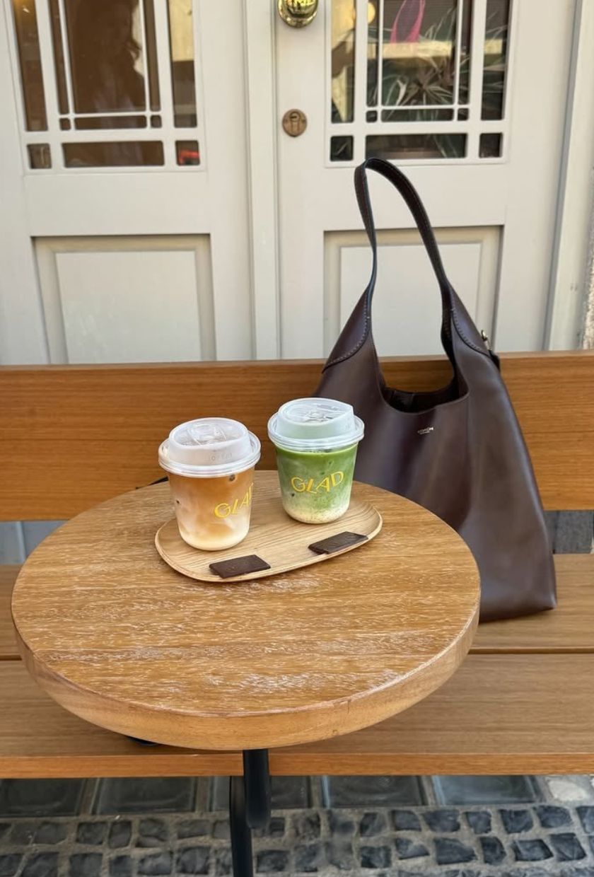 Coach Brooklyn bag on bench with coffee and matcha on table
