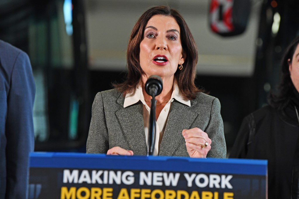 New York Governor Kathy Hochul speaks at a podium with a microphone, announcing transit savings.
