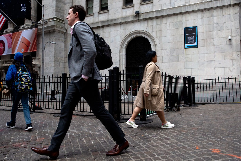 Workers and tourists walk past the New York Stock Exchange on Wall Street.