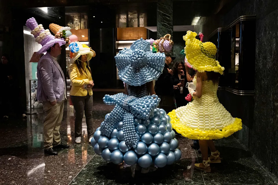 People wearing balloon costumes stand inside a building at Rockefeller Center during heavy rainfall at the Easter Parade and Bonnet Festival on Fifth Avenue, Sunday, April 5, 2026 in New York. (AP Photo/Adam Gray)
