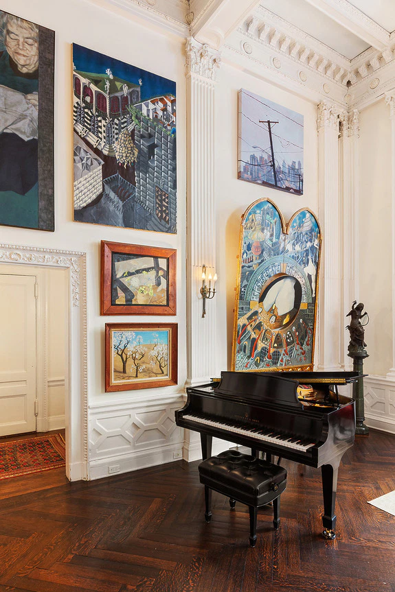 Elegant room with an artistic gallery wall and a grand piano in the center on polished wooden floors.