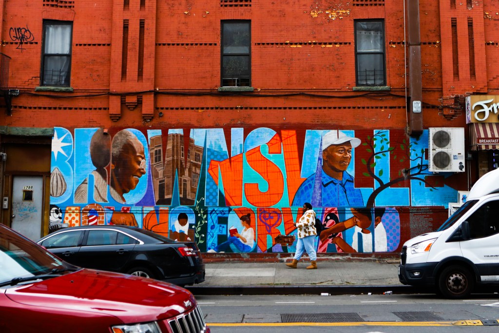 People walk through Brownsville, Brooklyn mural