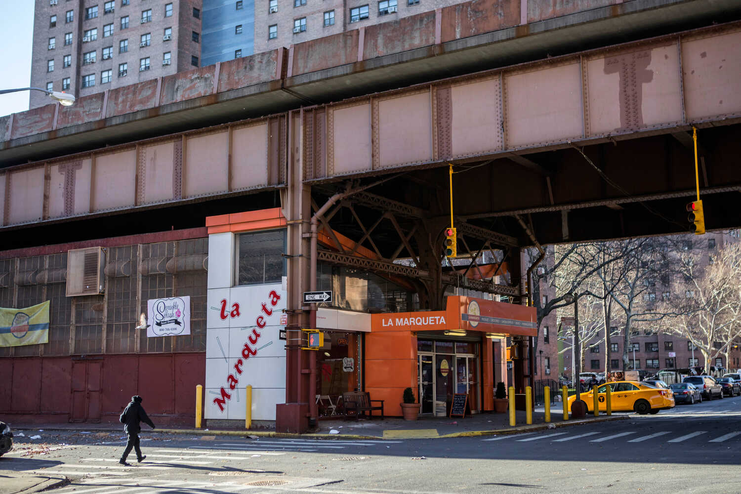 An orange building labeled La Marqueta is seen under elevated train tracks in Manhattan.