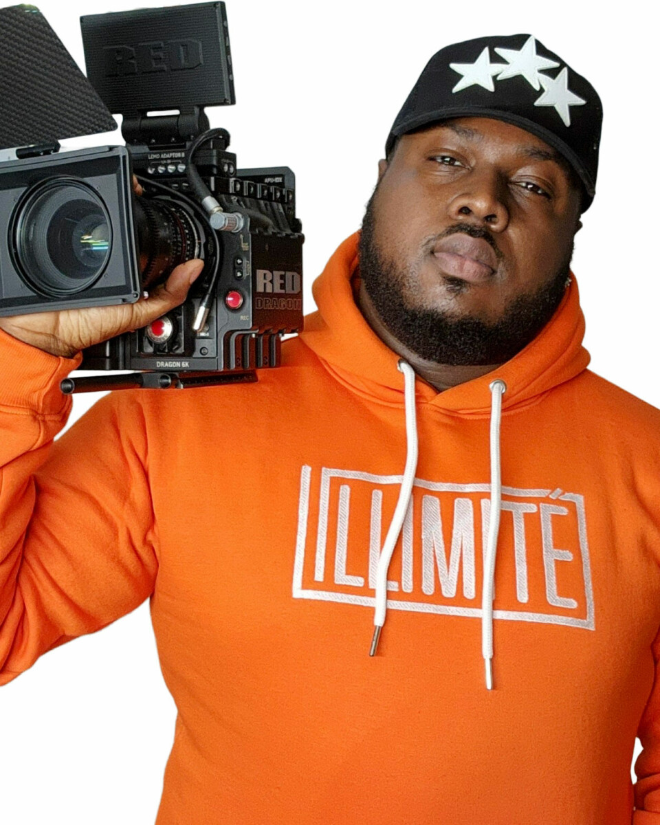 Man in orange ILLIMITÉ hoodie holding a RED cinema camera on his shoulder